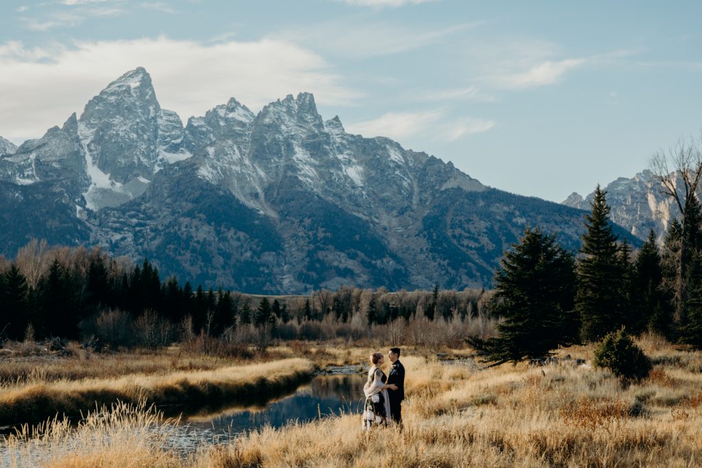 Couple in non-traditional wedding attire embrace after their Grand Teton National Park elopement at Schwabacher Landing