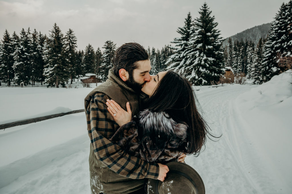 Couple kiss on Trail Creek Ranch in Jackson Hole Wyoming during their engagement photos with Erin Wheat