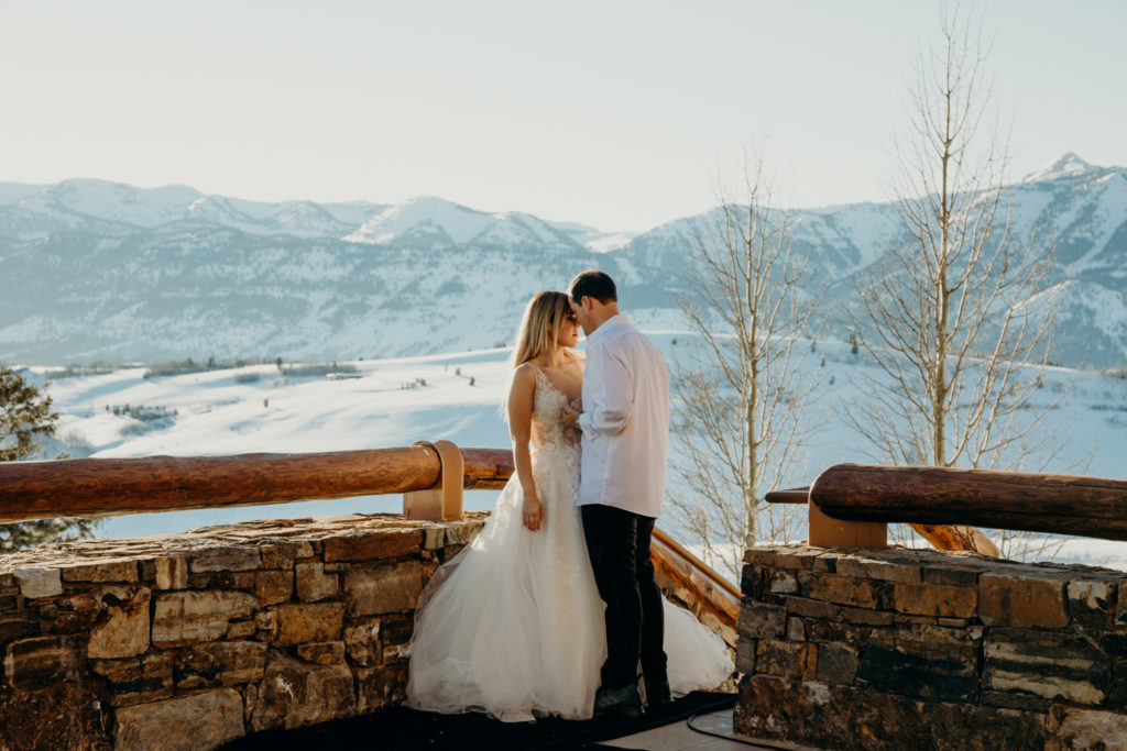 couple pose face to face in wedding attire at Amangani resort in Jackson Hole Wyoming at sunset